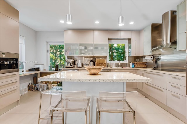 kitchen featuring tasteful backsplash, wall chimney range hood, a breakfast bar area, light tile patterned flooring, and black electric cooktop