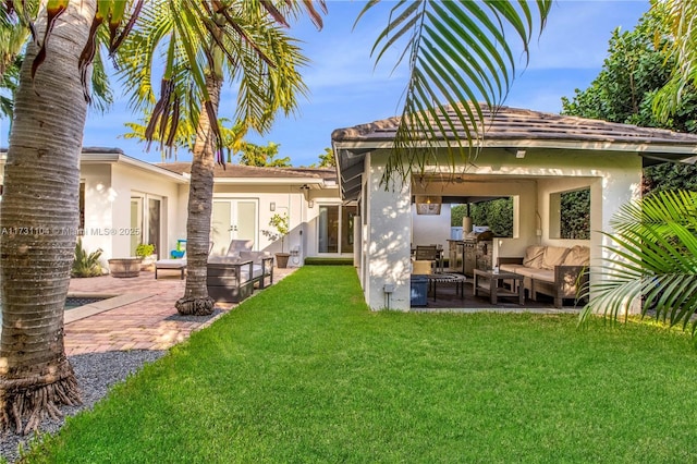 back of house featuring an outdoor living space, a yard, and stucco siding