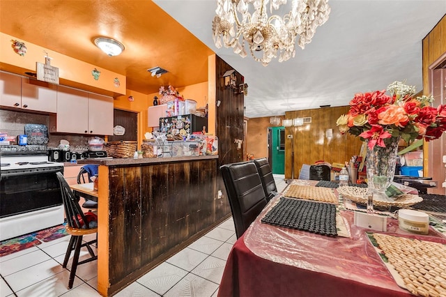 kitchen featuring decorative backsplash, electric stove, light tile patterned floors, and wood walls