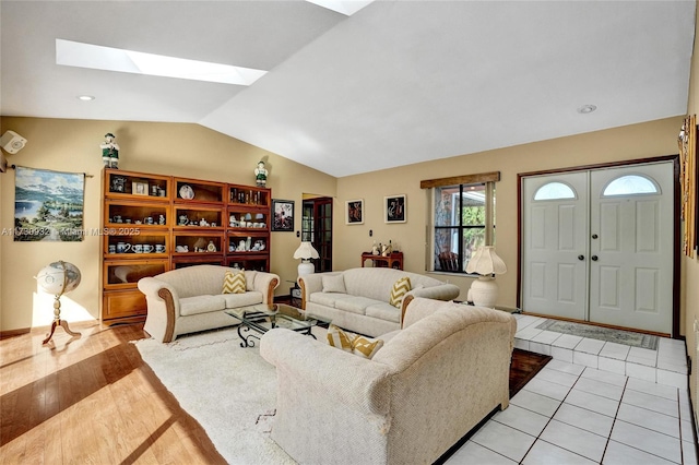 living room with lofted ceiling with skylight and light tile patterned floors