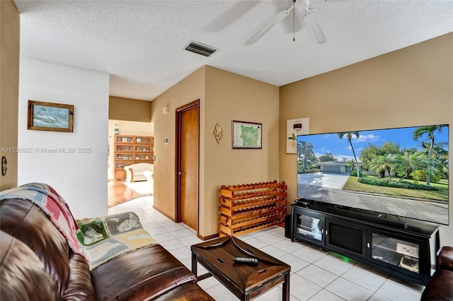 tiled living room featuring ceiling fan and a textured ceiling