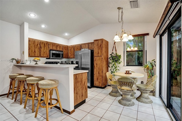 kitchen with a chandelier, vaulted ceiling, hanging light fixtures, appliances with stainless steel finishes, and kitchen peninsula