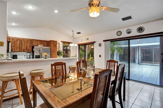 tiled dining room with vaulted ceiling, ceiling fan with notable chandelier, and a textured ceiling