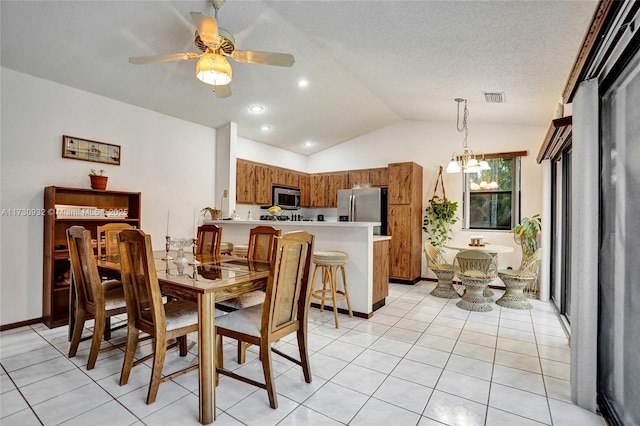 tiled dining space featuring ceiling fan with notable chandelier, vaulted ceiling, and a textured ceiling