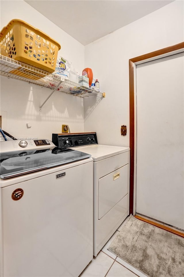 laundry area with light tile patterned floors and washing machine and clothes dryer