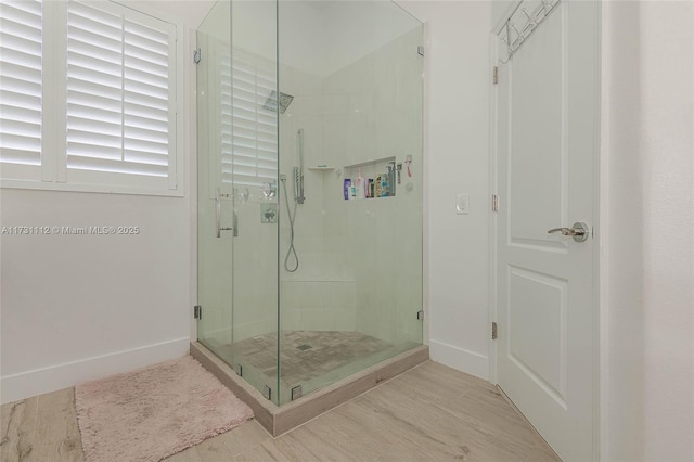 bathroom featuring a shower with shower door and wood-type flooring