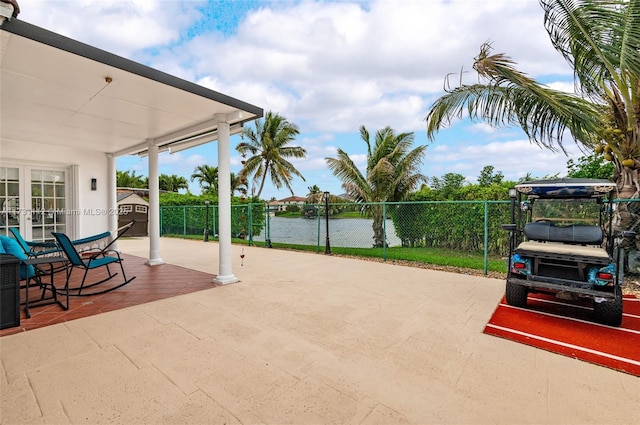 view of patio with french doors, a water view, and a storage unit