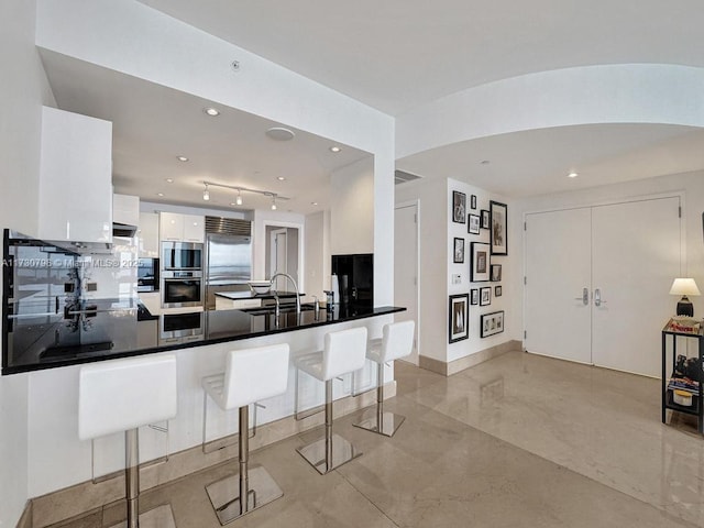 kitchen featuring a breakfast bar, white cabinetry, appliances with stainless steel finishes, and kitchen peninsula