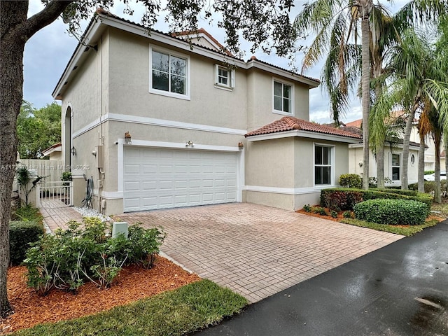 view of front of property with a tiled roof, decorative driveway, a garage, and stucco siding