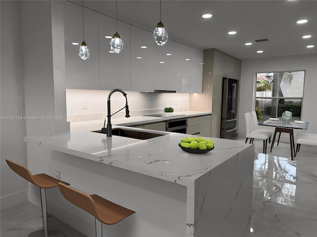 kitchen with a sink, freestanding refrigerator, recessed lighting, and modern cabinets