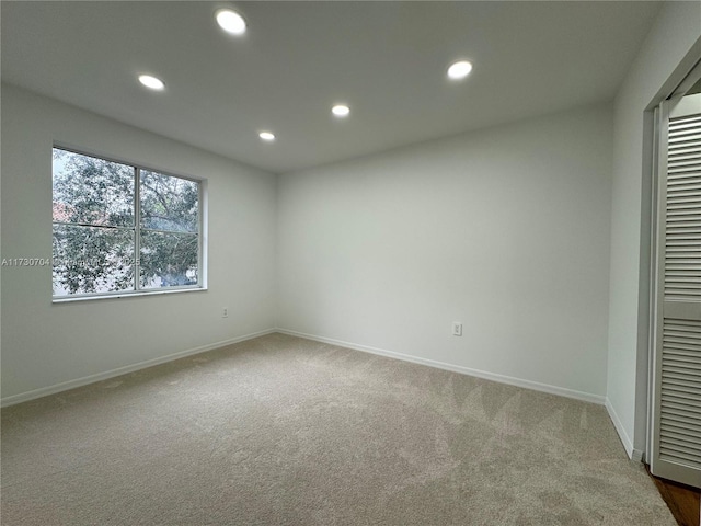 carpeted empty room featuring baseboards and recessed lighting