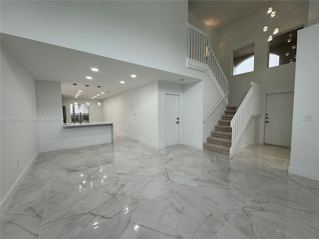 unfurnished living room featuring recessed lighting, stairway, a high ceiling, marble finish floor, and baseboards