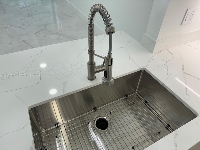 details featuring a sink and light stone counters