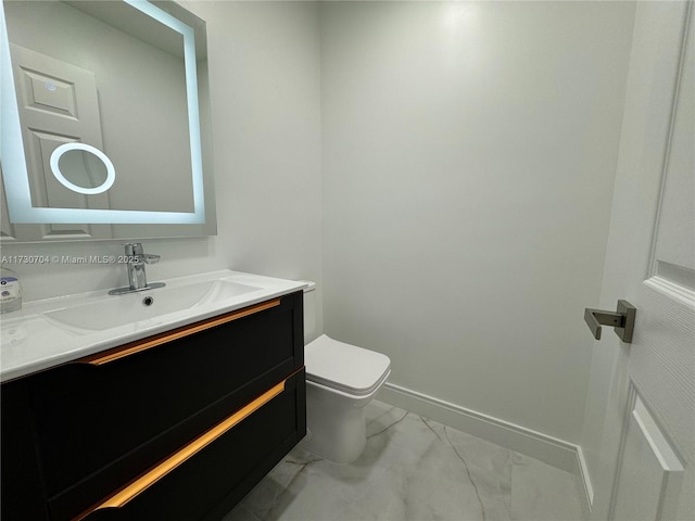 half bath featuring vanity, marble finish floor, baseboards, and toilet