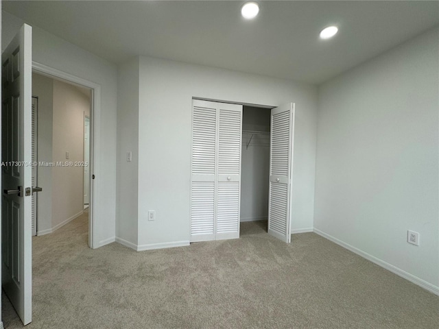 unfurnished bedroom with light carpet and a closet