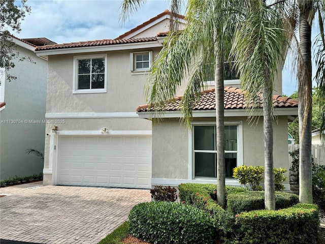exterior space with an attached garage, stucco siding, a tile roof, and decorative driveway