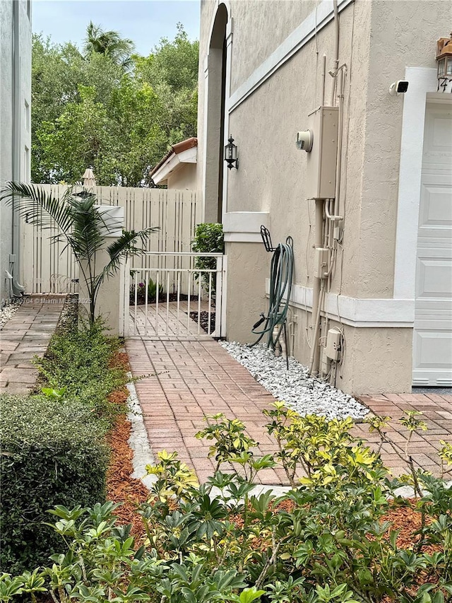 view of side of home with stucco siding and fence
