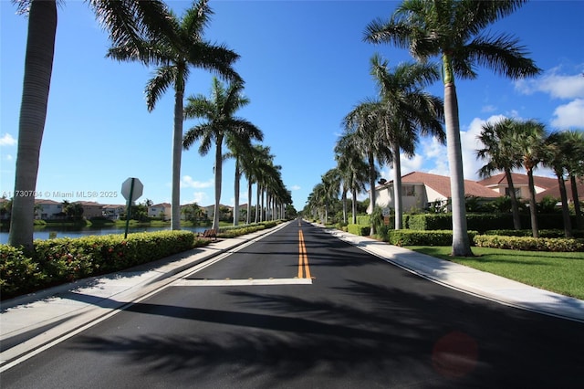 view of street with a water view, sidewalks, a residential view, and traffic signs