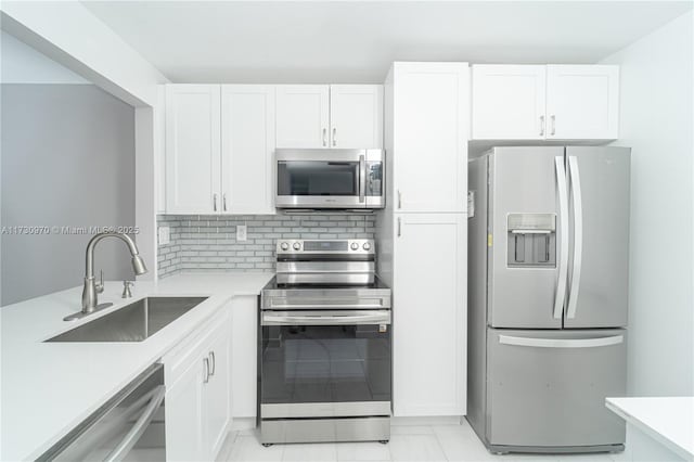 kitchen with sink, stainless steel appliances, white cabinets, and tasteful backsplash