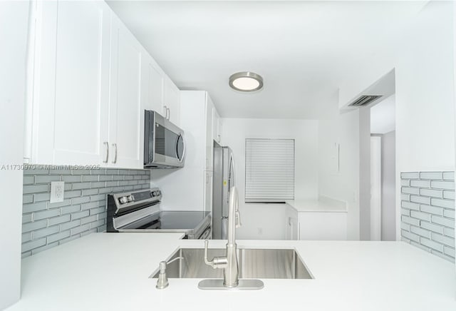 kitchen with sink, backsplash, white cabinets, and appliances with stainless steel finishes