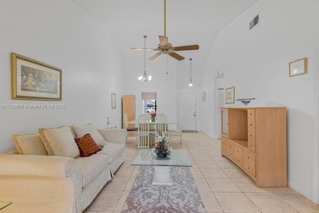 tiled living room with high vaulted ceiling and ceiling fan with notable chandelier