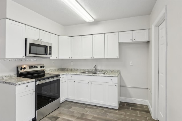 kitchen with sink, white cabinetry, a textured ceiling, and stainless steel appliances