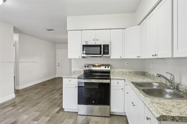 kitchen with sink, white cabinetry, appliances with stainless steel finishes, and light wood-type flooring