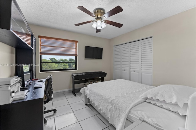 bedroom with a closet, ceiling fan, light tile patterned floors, and a textured ceiling