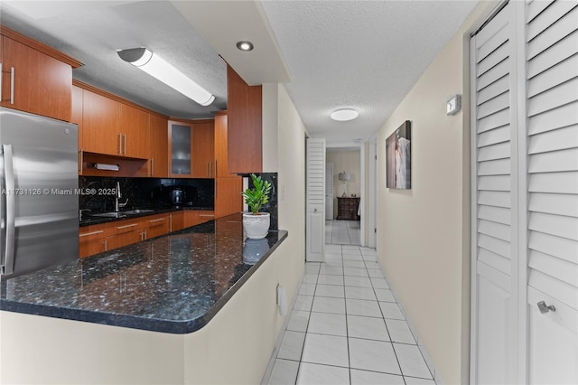 kitchen with sink, tasteful backsplash, light tile patterned floors, a textured ceiling, and stainless steel refrigerator