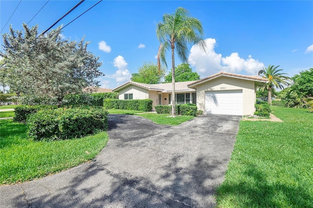 ranch-style home with a tile roof, a garage, stucco siding, a front yard, and concrete driveway