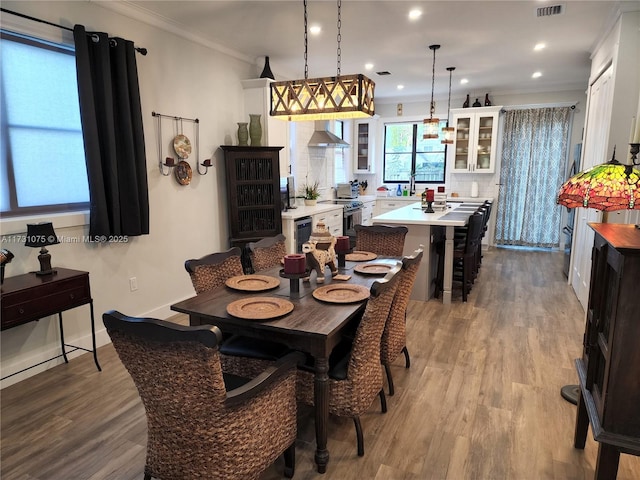 dining room featuring sink, light hardwood / wood-style flooring, and ornamental molding