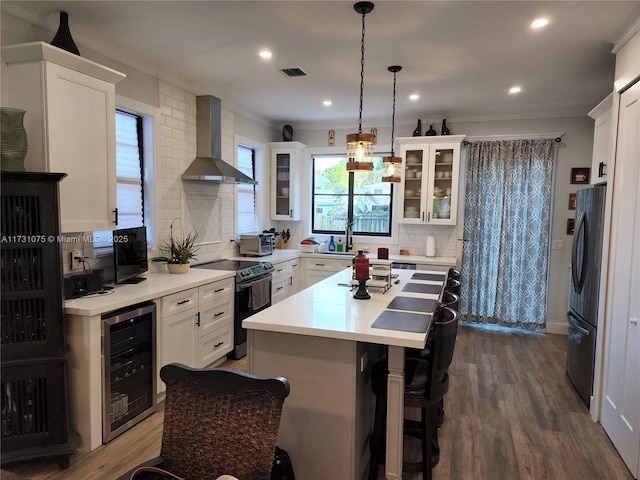 kitchen featuring wall chimney exhaust hood, decorative light fixtures, wine cooler, black electric range oven, and fridge