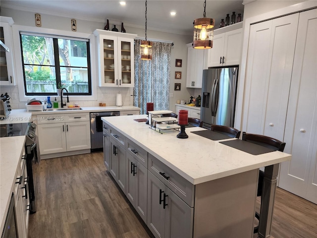 kitchen with pendant lighting, dishwasher, white cabinetry, an island with sink, and stainless steel fridge