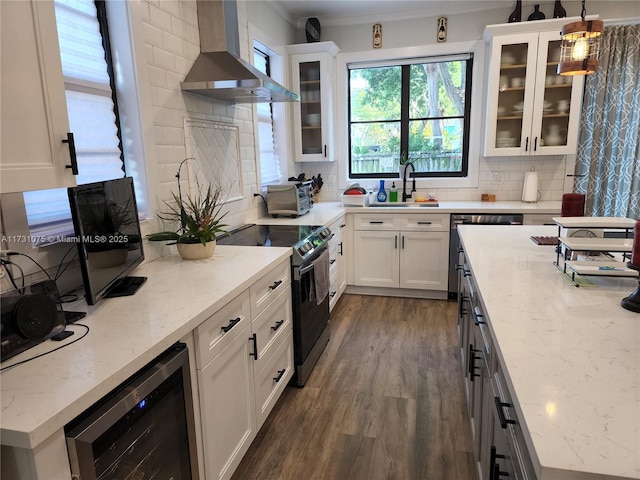 kitchen featuring range with electric stovetop, hanging light fixtures, wine cooler, backsplash, and wall chimney range hood