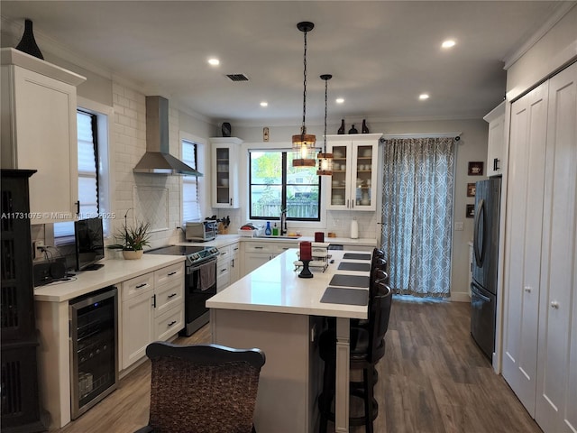 kitchen with tasteful backsplash, white cabinetry, wall chimney range hood, electric range oven, and beverage cooler