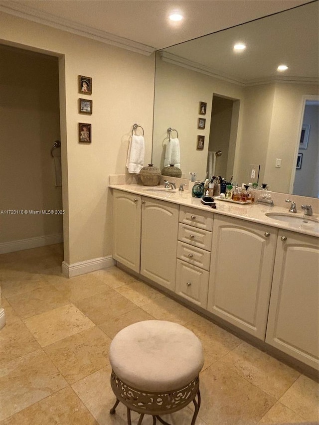 bathroom with double vanity, crown molding, baseboards, and a sink