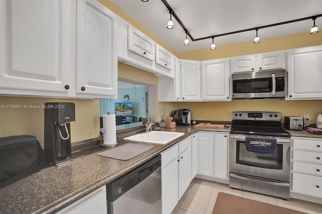 kitchen with appliances with stainless steel finishes, sink, white cabinetry, light tile patterned floors, and track lighting