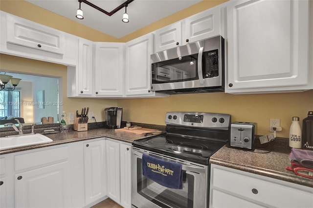 kitchen with sink, stainless steel appliances, white cabinetry, and track lighting