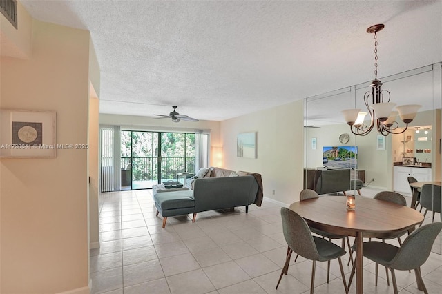 tiled dining space featuring ceiling fan with notable chandelier and a textured ceiling