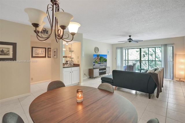 dining area featuring sink, ceiling fan with notable chandelier, light tile patterned floors, and a textured ceiling