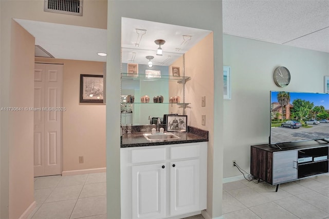 bar featuring white cabinets, light tile patterned floors, a textured ceiling, and sink