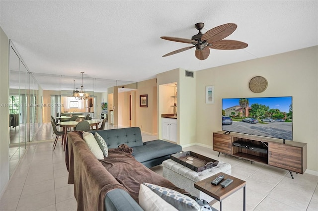 living room featuring a textured ceiling, light tile patterned floors, and ceiling fan