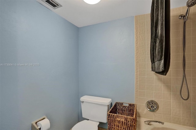 bathroom with toilet and tiled shower / bath combo