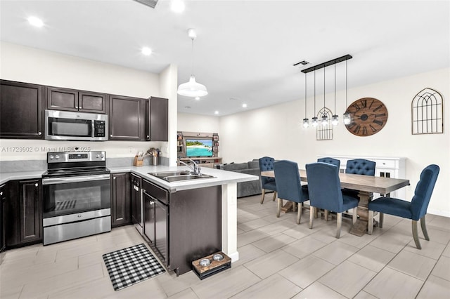 kitchen with sink, dark brown cabinets, kitchen peninsula, pendant lighting, and stainless steel appliances