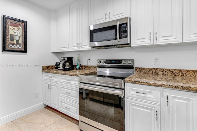 kitchen with light tile patterned flooring, white cabinets, dark stone counters, and stainless steel appliances