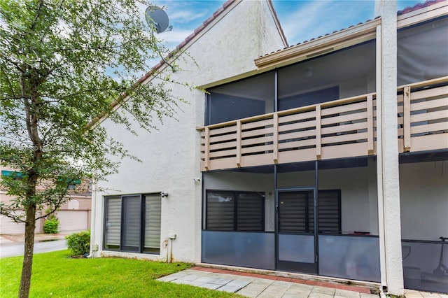 back of property with a balcony and a yard