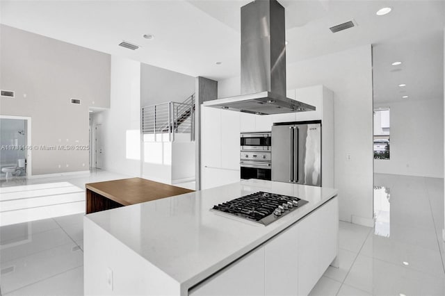 kitchen featuring white cabinetry, island range hood, light tile patterned floors, a kitchen island, and stainless steel appliances