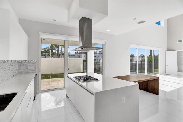 kitchen featuring white cabinetry, island range hood, light tile patterned floors, a kitchen island, and stainless steel gas stovetop