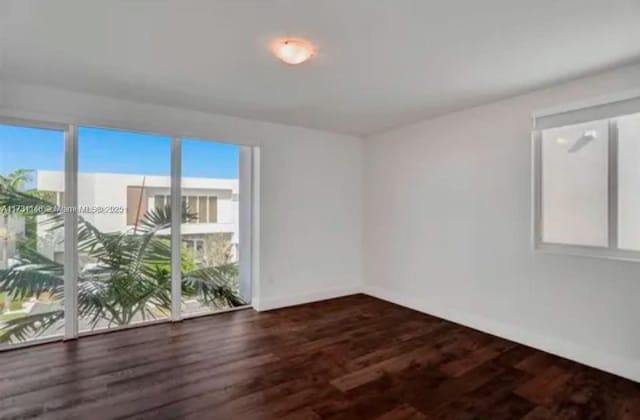 unfurnished room with dark hardwood / wood-style flooring and a healthy amount of sunlight