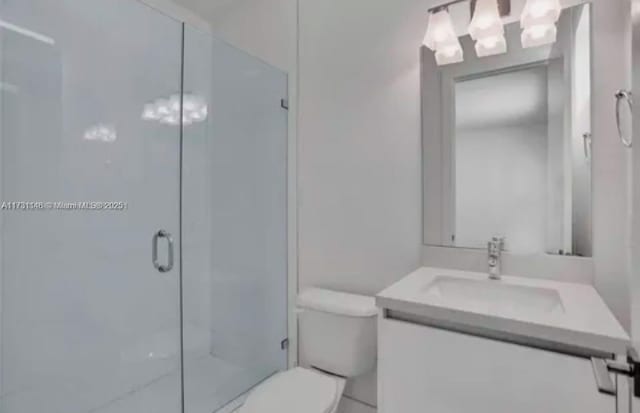 bathroom with vanity, a shower with shower door, and toilet